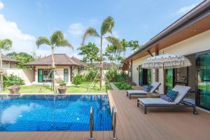 a villa with a swimming pool with two chairs and an umbrella at Tranquil 4BR Garden Pool Oasis - Layan Beach in Laguna Phuket