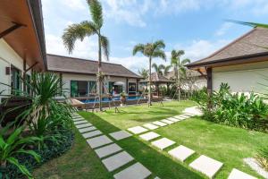 a backyard with a lawn and a swimming pool at Tranquil 4BR Garden Pool Oasis - Layan Beach in Laguna Phuket