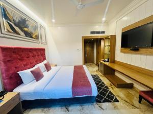 a bedroom with a large bed and a flat screen tv at Hotel Airport Centre Point in Nagpur