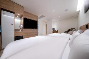 a bedroom with two white beds and a flat screen tv at 루엠호텔안산 in Ansan