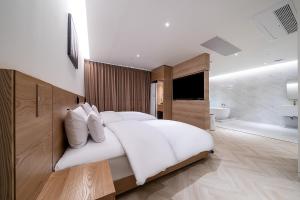 a bedroom with a large white bed and a bathroom at 루엠호텔안산 in Ansan