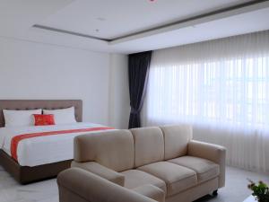a bedroom with a bed and a couch at Grand Elhajj Banten in Tjipondoh Tiga +1 photo