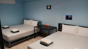 two beds in a room with a desk between them at Dee-maak Hostel in Thong Sala +51 photos