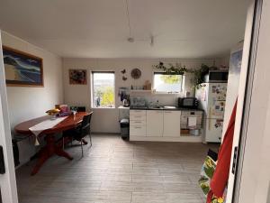 a kitchen with a table and a kitchen with a refrigerator at Sunsets on Harbour Kauri or Totara Cabin in Matarangi