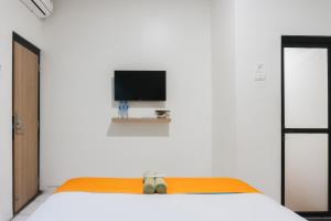 a bedroom with a bed with a flat screen tv at Sans Stay Eskole Lampung in Geruntang