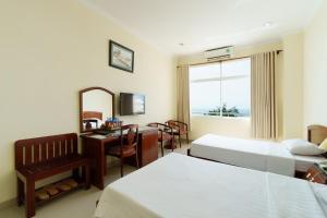a hotel room with two beds and a desk and a mirror at Victory Hotel Old Wing in Vung Tau