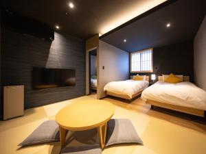 a bedroom with two beds and a table and a tv at Yufuin Covaco in Yufu