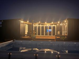 a house lit up at night with lights on it at Sunsets on Harbour Kauri or Totara Cabin in Matarangi