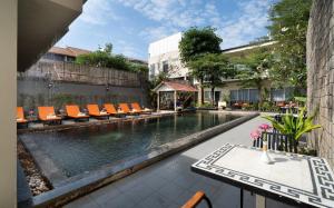 a swimming pool with orange chairs and a table at Indochine Sanctuary Hotel in Siem Reap