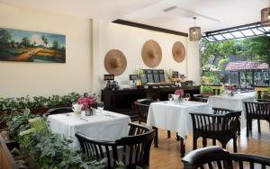 a restaurant with white tables and chairs and a piano at Indochine Sanctuary Hotel in Siem Reap