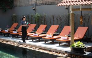 a woman standing next to a row of chairs next to a pool at Indochine Sanctuary Hotel in Siem Reap