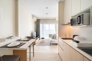 a kitchen with white cabinets and a living room at 2BR Family Condo - Veranda Pattaya - Beachfront in Na Jomtien