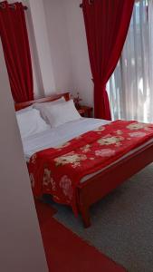 a bedroom with a red bed with red curtains at Stay Logi Nanuoya in Nanu Oya