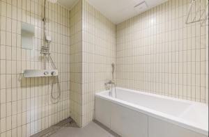a white tiled bathroom with a tub and a shower at Daegu Hound Hotel Dongchon Amusement Park in Daegu +28 photos