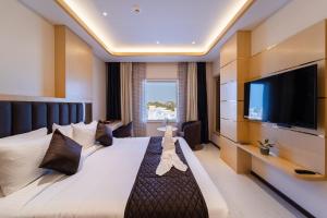 a hotel room with a large bed and a flat screen tv at Ratan International in Pondicherry