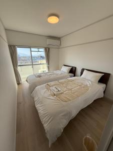 two beds in a room with a large window at OtowaBase in Kofu