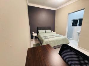 a bedroom with a bed and a table in it at Pholanathi Lodge in Cliffdale