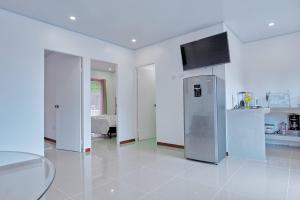 a white kitchen with a stainless steel refrigerator at Butterfly House - Centric 2BR with shared pool in Puerto Viejo