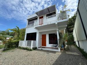 a white house with a balcony next to a building at Butterfly House - Centric 2BR with shared pool in Puerto Viejo
