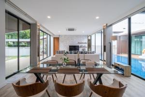 a living room with a glass table and chairs at Movenpick Residences 4-Bedroom Pool Villa Beach Access, Na Jomtien Pattaya in Na Jomtien