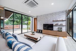 a living room with a white couch and a tv at Movenpick Residences 4-Bedroom Pool Villa Beach Access, Na Jomtien Pattaya in Na Jomtien
