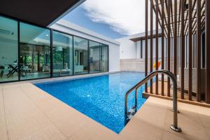an indoor swimming pool in a house with glass walls at Movenpick Residences 4-Bedroom Pool Villa Beach Access, Na Jomtien Pattaya in Na Jomtien