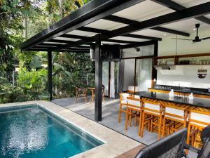 an outdoor dining area with a table and chairs and a swimming pool at Sharka House - Playa Negra 2BR with pool & AC in Puerto Viejo