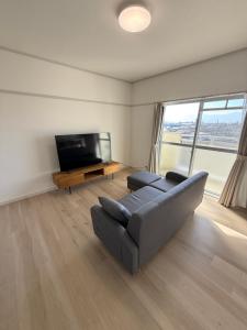 a living room with a couch and a flat screen tv at OtowaBase in Kofu