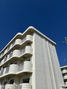 a white building with balconies and a blue sky at OtowaBase in Kofu