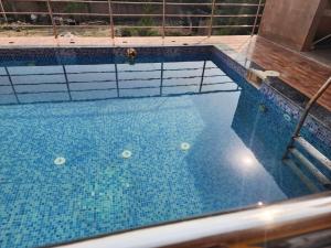 a large swimming pool with blue tiles on top of it at Paromita inn in Tajpur