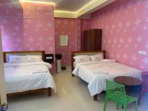 two beds in a room with pink walls and a table at KH Residency And Lodging in Punganūru