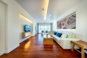 a living room with a white couch and a tv at Jomtien Palm Beach Hotel & Resort - Family-Friendly in Jomtien Beach