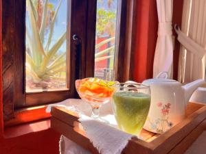 a wooden tray with a glass of juice and a drink at Posada del Cortes in Loreto
