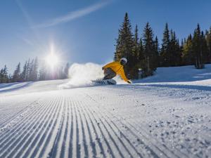 a man riding a snowboard down a snow covered slope at Aspenwood - CoralTree Residence Collection in Snowmass Village