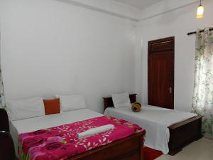 a bedroom with two beds with pink sheets at Ninety Nine Grand Hotel in Badulla