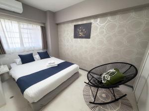 a bedroom with a bed and a chair in it at BALCOM STAY Hiroshima Deshio in Hiroshima
