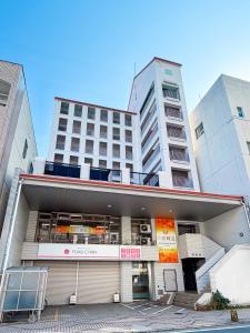 a large apartment building with a parking lot in front of it at BALCOM STAY Hiroshima Deshio in Hiroshima