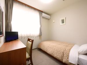 a bedroom with a bed and a desk with a computer at Hotel M&M Soma in Soma