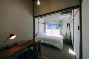 a bedroom with a bed and a desk and a window at Public Guest House in Karuizawa