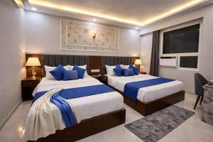 a hotel room with two beds with blue pillows at Hotel Royal Dot, Haridwar in Haridwār