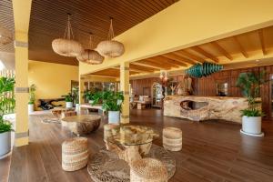 a lobby with couches and tables and a stone wall at Chaykha Retreat Phuket in Chalong