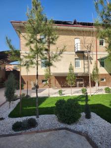 a courtyard with trees and a building in the background at Maximum Hotel in Navoi