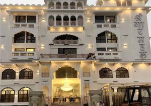 a large white building with lights on it at Hotel Shringar Mahal Vrindavan in Chhatikara
