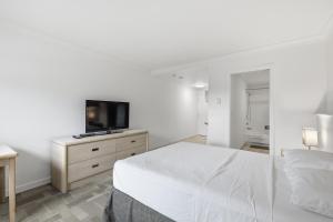 a white bedroom with a bed and a flat screen tv at Lillooet Hotel Victoria in Lillooet