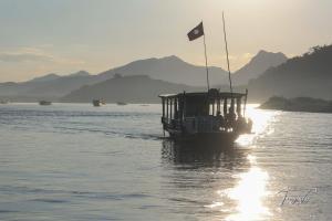 a boat with a flag on the water at Mekong Backpackers in Pakbeng
