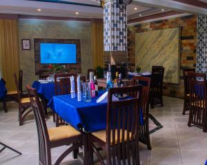 a dining room with blue tables and chairs and a tv at Meltonia Luxury Inn in Busia
