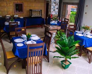 a restaurant with blue tables and chairs and a plant at Meltonia Luxury Inn in Busia