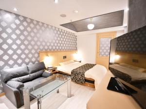 a hotel room with a couch and a bed at ホテル ヴォーグ in Kuwana