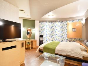 a bedroom with a bed and a flat screen tv at ホテル ヴォーグ in Kuwana