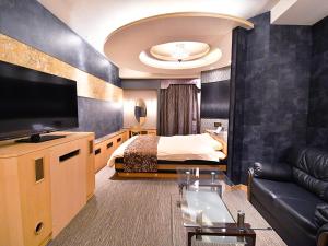 a hotel room with a bed and a tv at ホテル ヴォーグ in Kuwana